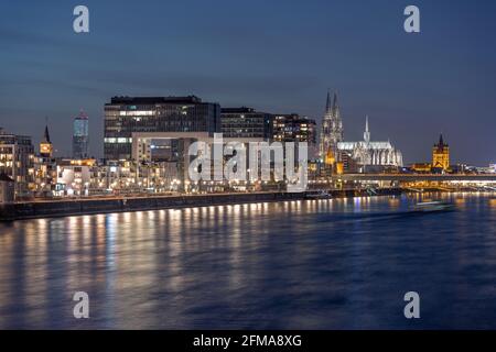 Kranhäuser am Rheinufer in der Abenddämmerung, mit dem Kölner Dom im Hintergrund Stockfoto