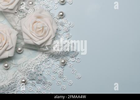 Weiße Perlen und Spitze auf einem hellblauen Hintergrund mit Weiße künstliche Rosen für das Konzept der Romantik oder Hochzeit Stockfoto