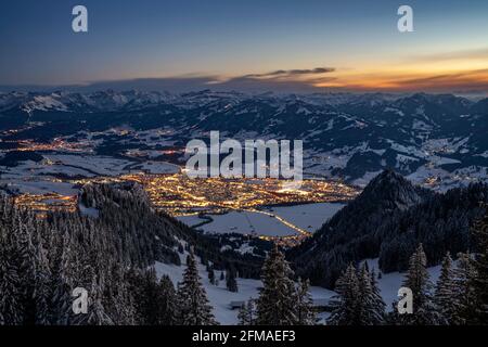 Sonthofen, beleuchtet in der Dämmerung an einem kalten Winterabend, von den Grünten aus gesehen. Eingerahmt von den schneebedeckten Allgäuer Alpen unter blauem Himmel. Bayern, Deutschland, Europa Stockfoto