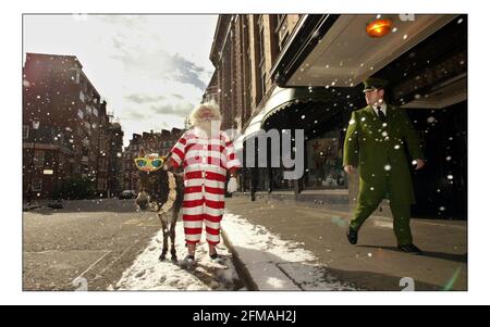 Vater Weihnachten und sein Seesel Dino posieren für Fotos vor einem schneebedeckten Harrods, bevor sie die Gäste am 9. August 2005 in London, England, im dritten Stock des Knightsbridge Stores auf eine Tour durch die Weihnachtswelt nehmen. Über 15.000ft qm Fläche sind Weihnachten im gesamten Geschäft gewidmet. Mit einer künstlichen Schneemaschine, die gegen die Sommerwärme kämpft, kommen Pater Christmas und sein Seesel Dino vor einem schneebedeckten Eingang nach Harrods zum Start von Christmas World im Knightsbridge Store in London an. Bild David Sandison 9/8/2005 Stockfoto