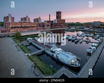 Sonnenuntergang mit violetten Wolken am Tempelhofer Hafen mit Spiegelung des Ullsteinhauses in Berlin. Stockfoto