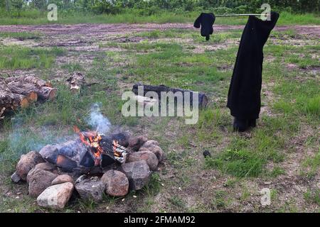 Verschiedene Kleidungsstücke trocknen am Lagerfeuer Stockfoto