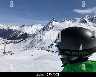 Skifahrer schaut nach Galtür, Kind, Helm, Skigebiet Galtür, Silvapark, Silvretta, Skipiste, Berge, Winterlandschaft, Verwallgruppe, Galtür, Paznauntal, Tirol, Österreich Stockfoto