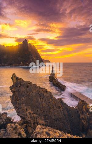 Vertikale Aufnahme des Sonnenuntergangs am Leuchtturm in der Gemeinde Pasajes San Juan, Gipuzkoa, Spanien Stockfoto