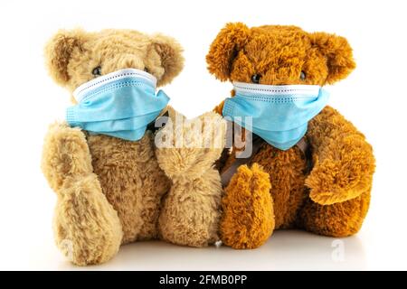 Zwei Teddybären mit Schutzmaske, Teddybär sitzen in blauen medizinischen Masken auf weißem Hintergrund, Konzept des Schutzes vor Atemdise Stockfoto