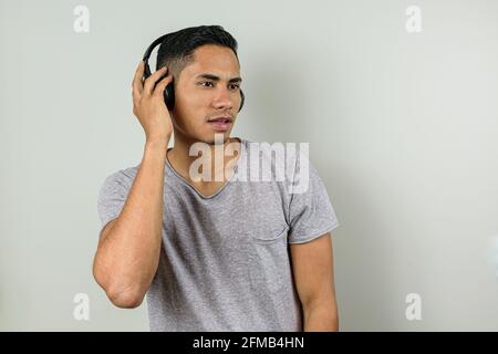 28-jähriger Brasilianer mit kabellosem Kopfhörer, Musik hören und zur Seite schauen. Stockfoto