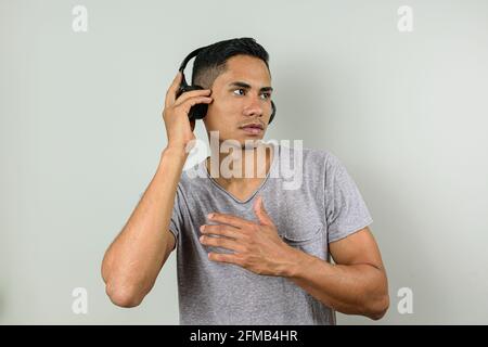 Der 28-jährige Brasilianer mit einer Hand auf dem kabellosen Kopfhörer ist bereit für eine Action-Bewegung. Stockfoto