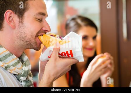 Hotdog - junge Kunden in einer Snackbar essen leckere Fastfood Würstchen Stockfoto