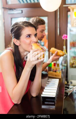 Hotdog - junge Kunden in einer Snackbar essen leckere Fastfood Würstchen Stockfoto