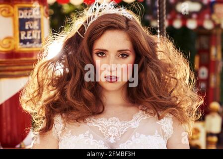 Junge Frau mit roten Haaren und Sommersprossen auf einem nostalgischen Karussell Stockfoto