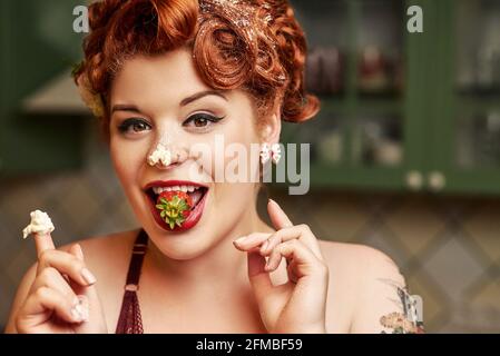 Pin-up Mädchen mit roten Haaren Backen in der Küche Stockfoto