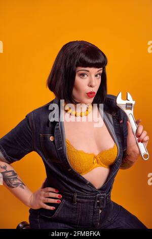 Tätowierte kurvige Modell mit schwarzen Haaren in Pin-up-Stil als Ein Mechaniker Stockfoto