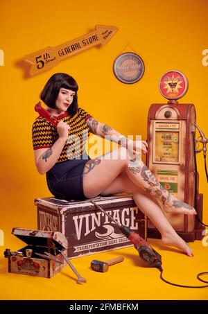 Tätowierte kurvige Modell mit schwarzen Haaren in Pin-up-Stil als Ein Mechaniker Stockfoto