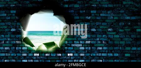 Loch in einer Ziegelmauer mit Blick auf den Strand Stockfoto