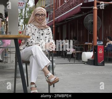 Muslimische Frau in modischem Kleid sitzt in Little Chinatown in Jakarta, Indonesien Stockfoto