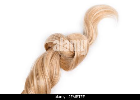 Blonde Haarknoten in Form von Herz, isoliert auf weißem Hintergrund. Strang aus honigblondem Haar, Draufsicht. Friseurservice, Haarstärke, Haarschnitt, h Stockfoto