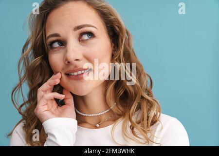 Blonde junge weiße Frau lächelt und schaut isoliert nach oben Blaue Wand Stockfoto