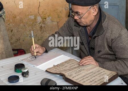 Älterer Mann, der in chinesischen Schriftzeichen schreibt, alte vietnamesische Ahnengebete, Lao VA Chai Dorf der Dao (Zao) Ao Dai Minderheit, Ha Giang Stockfoto