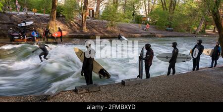 München, Deutschland. Mai 2021. Ein Surfer reitet auf der Eisbachwelle in der Prinzregentenstraße am Rande des Englischen Gartens, während andere Surfer auf ihren Slot warten. Der Freizeit-Hotspot ist das ganze Jahr über ein Magnet für Surfer und Zuschauer. Kredit: Peter Kneffel/dpa/Alamy Live Nachrichten Stockfoto