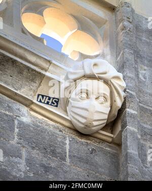 Geschnitzte Steinskulptur auf Christchurch Priorat EINES National Health Service, NHS, Krankenschwester trägt EINE PSA Maske in Bezug auf die Covid-19 Coronavirus Pande Stockfoto