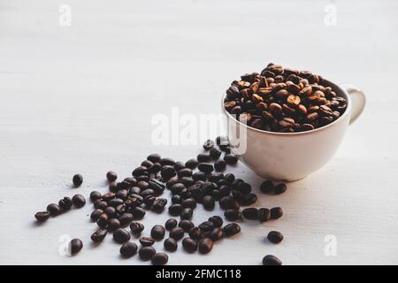 Geröstete Kaffeebohnen in einer Kaffeetasse auf einem weißen Tabelle Stockfoto