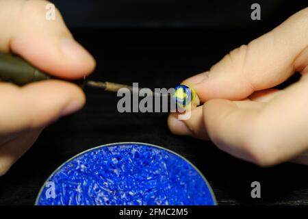 Zahntechniker modelliert Zahnkronen mit heißem Wachs. Die Hände eines Zahntechnikers aus der Nähe. Arbeitsplatz eines Zahntechnikers Stockfoto