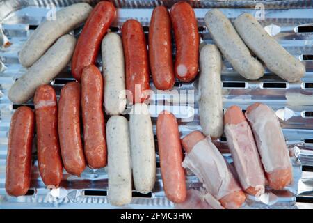 Erholung im Freien. Sommerfest. Rohwürste zum Grillieren auf einer Aluminiumfolie liegend Stockfoto