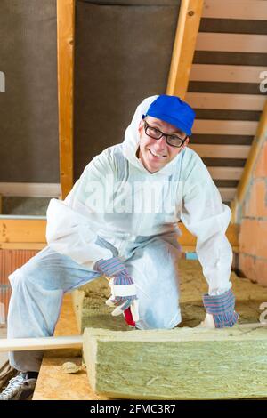 Arbeitnehmer insgesamt ist isolierendes Material mit Handschuhen und Messer schneiden. Stockfoto