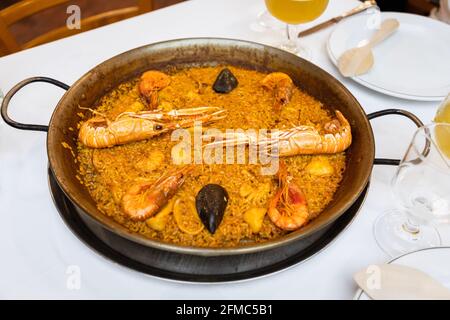 Köstliche Paella mit traditionellen valencianischen Meeresfrüchten (herzhaftes Reisgericht mit Garnelen, Tintenfisch und Muscheln) in der Paella-Pfanne Stockfoto