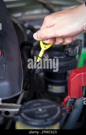 Nahaufnahme Hand ziehen Motorölmessstab. Mechaniker überprüft den Ölstand des Motors in einem Fahrzeug mit geöffneter Motorhaube. Reparatur von Autoservice Stockfoto