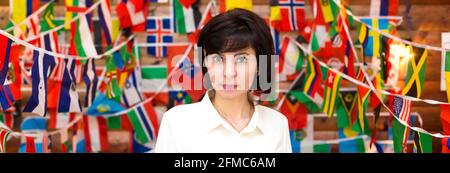 Seriöse Geschäftsfrau runzelte die Stirn auf dem Hintergrund der Fahnenwand. Stockfoto