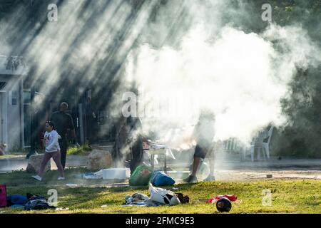 Tel Aviv, Israel - 31. März 2021: Zwei Männer bereiten an einem sonnigen Morgen in einem Park in Tel Aviv ein Barbecue vor. Stockfoto