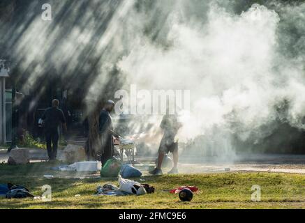 Tel Aviv, Israel - 31. März 2021: Zwei Männer bereiten an einem sonnigen Morgen in einem Park in Tel Aviv ein Barbecue vor. Stockfoto