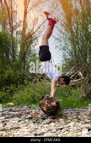 Junge Teenager, die auf dem Feld trainieren und ausbalancierende Übungen durchführen Auf einem gefallenen Ast bei Sonnenuntergang mit selektivem Fokus Stockfoto
