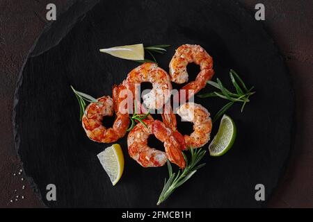 Draufsicht auf gebratene Garnelenschwänze mit Zitrone und Rosmarin Auf Schiefertafel Stockfoto