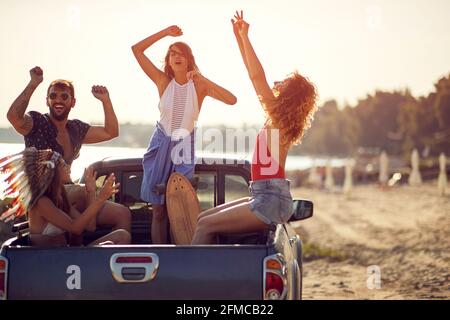 Eine Gruppe fröhlicher Freunde macht sich an einem schönen Sommertag am Meer auf dem Rücken eines Autos lustig. Sommer, Meer, Urlaub, Freundschaft Stockfoto