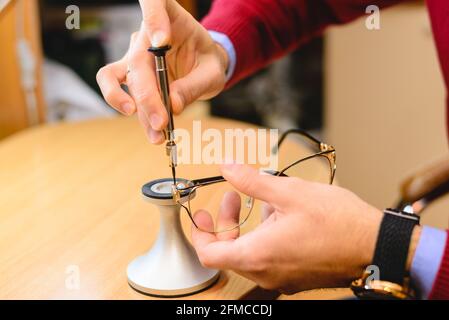 Nahaufnahme der Hände eines männlichen Optikers/Optometristen, der die Brille repariert Stockfoto