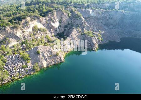 Felsige Ufer des Radon Lake an einem sonnigen Sommermorgen. Luftaufnahme eines alten überfluteten Granitsteinbruchs. Ein malerischer Teich. Stockfoto