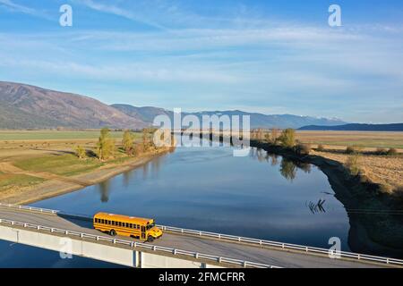 Schulbus, der im Frühjahr über den Kootenai River nach Copeland fährt. Boundary County, North Idaho. (Foto von Randy Beacham) Stockfoto