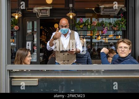 Die Abbildung zeigt einen Kellner, der auf den Außenterrassen von Bars und Restaurants Daumen nach oben gibt, Samstag, 08. Mai 2021, am Uferdamm (zeedijk, p Stockfoto