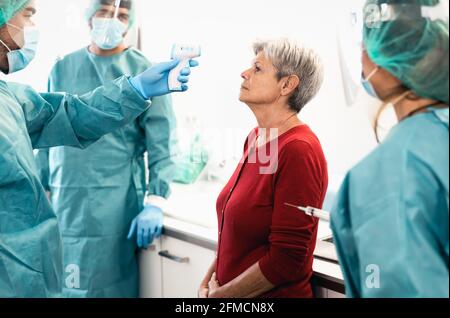 Arzt, der die Temperatur mit einem neuen Digitalthermometer für ältere Frauen misst Patient während des Wartens auf die Covid19-Impfdosis während des Corona-Virus Pandemie Stockfoto