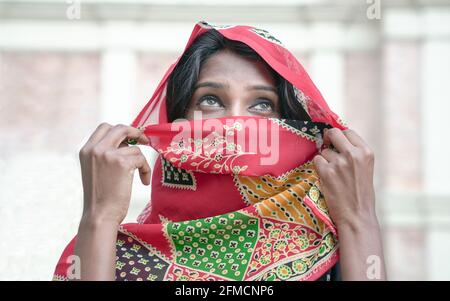 Schöne indische Frau mit traditionellem indischen Saree-Kostüm, Schleier bedeckt ihr Gesicht und enthüllt nur die Augen. Stockfoto