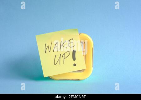 Wake-up-Nachricht auf Marker Pen Stick auf gelbe Uhr geschrieben. Auf blauem Hintergrund. Stockfoto