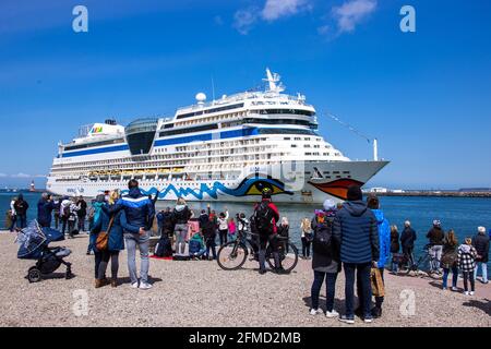 Rostock, Deutschland. Mai 2021. Die Bewohner der Hansestadt und Kreuzfahrtfans begrüßen das Kreuzschiff „AIDAsol“ bei der Einfahrt in den Hafen. Das Schiff kommt anlässlich der Nationalen Seeverkehrskonferenz am 10.05.2021 und der Einweihung des neuen Landkraftwerks nach Warnemünde. Quelle: Jens Büttner/dpa-Zentralbild/dpa/Alamy Live News Stockfoto