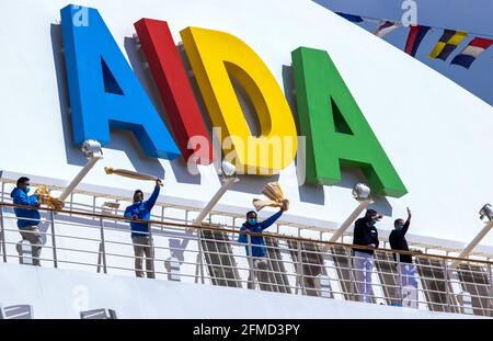 Rostock, Deutschland. Mai 2021. Die Crew-Mitglieder winken Badetücher von den Balkonen des Kreuzfahrtschiffs „AIDAsol“, wenn es in den Hafen einfährt. Das Schiff kommt anlässlich der Nationalen Seeverkehrskonferenz am 10.05.2021 und der Einweihung des neuen Landkraftwerks nach Warnemünde. Quelle: Jens Büttner/dpa-Zentralbild/dpa/Alamy Live News Stockfoto