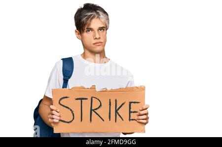 Junge hispanic Mann hält Streik Banner Karton Denken Haltung und Nüchterner Ausdruck, der selbstbewusst aussieht Stockfoto