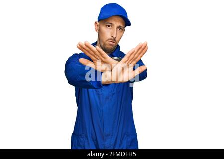 Glatze Mann mit Bart tragen Baumeister Jumpsuit einheitliche Ablehnung Ausdruck Kreuzung Arme und Handflächen tun negative Zeichen, wütend Gesicht Stockfoto