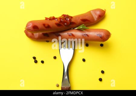 Gabel mit gegrillter Wurst auf gelbem Hintergrund Stockfoto