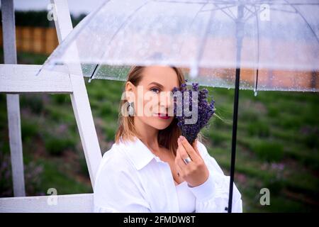 Romantisches Mädchen sammelt Strauß von Lavendel im Regen. Flache Tiefe des Feldes Foto Stockfoto