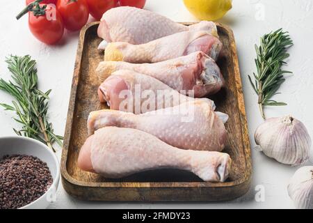 Rohe, ungekochte Hähnchenbeine, Drumsticks mit Zutaten, mit Rosmarin, Gewürzen und Gemüse, auf weißem Hintergrund Stockfoto